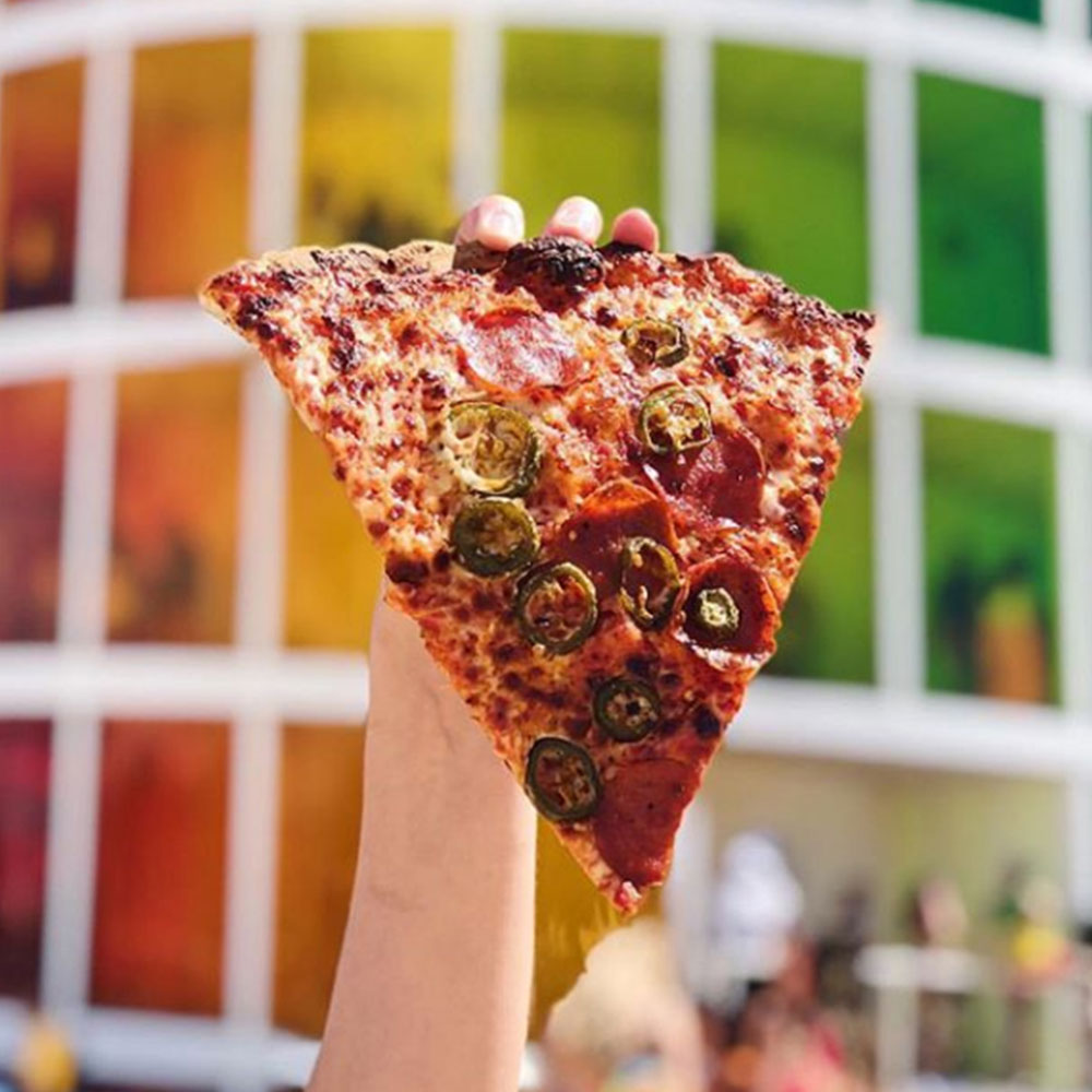Large pepperoni jalapeno pizza slice in front of Coachella installation